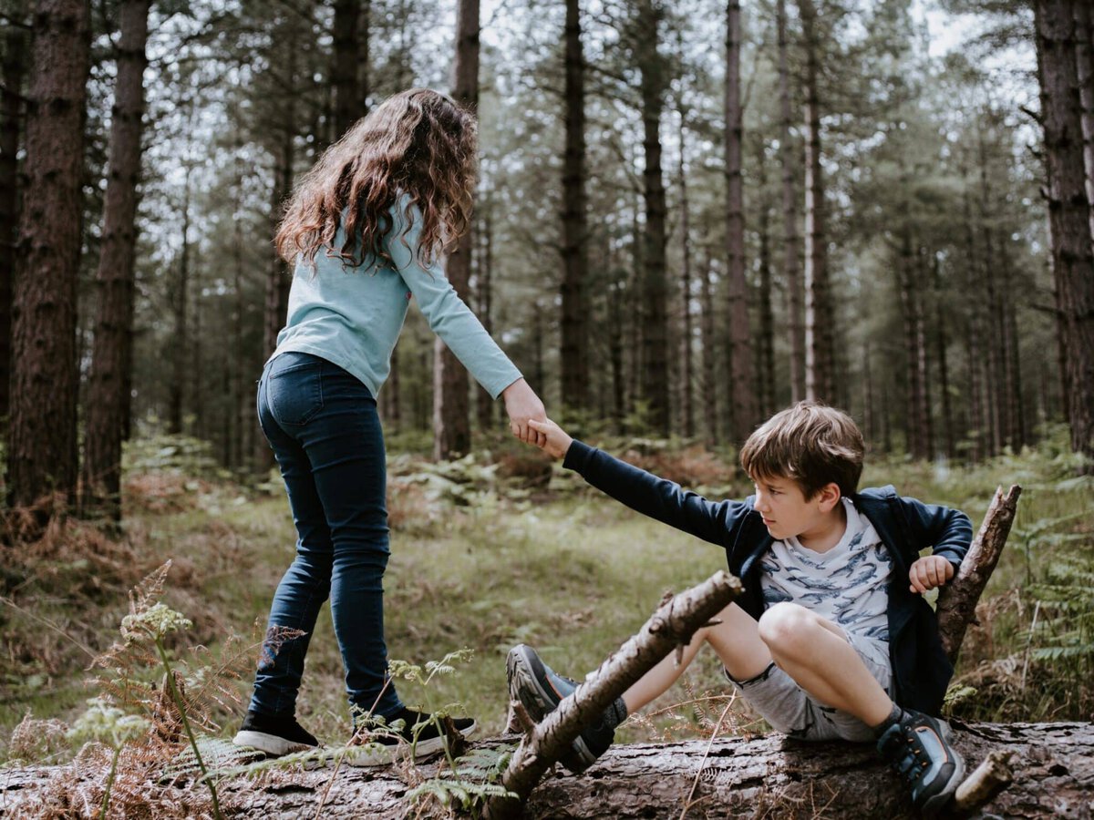Boy and girl playing on three tree log showing how to care for others more than yourself